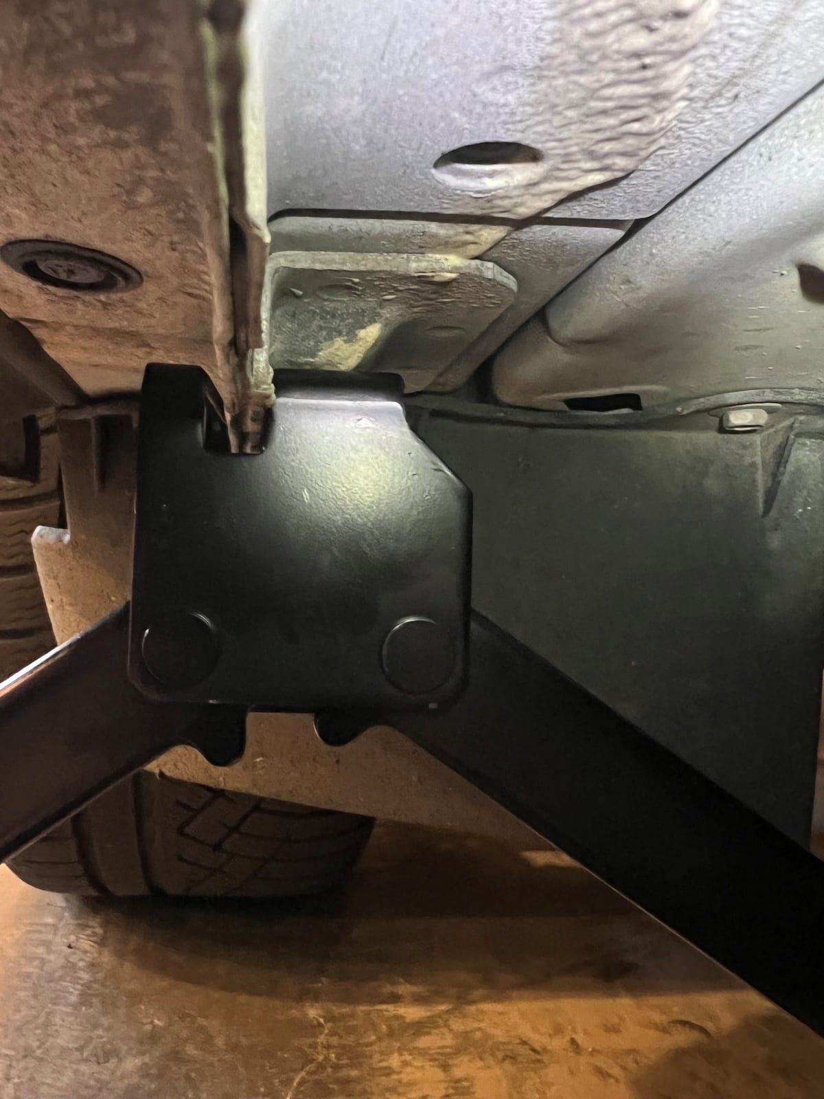 The factory jack's slotted head straddles the weld and seats between the two notches, right in line with that reinforced pad.